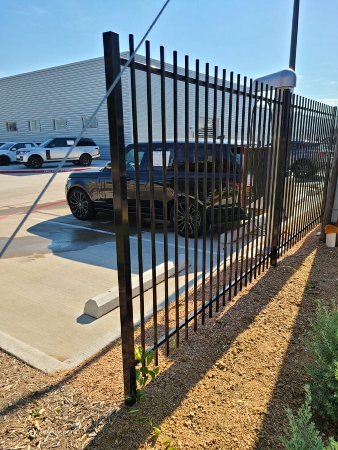 Black ornamental iron fence beside a parking lot